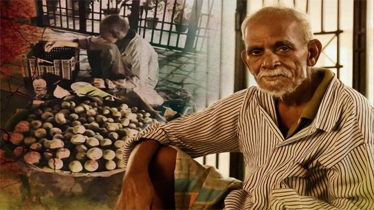 An old man struggles alone on the sidewalk of Gariahat, basket in hand